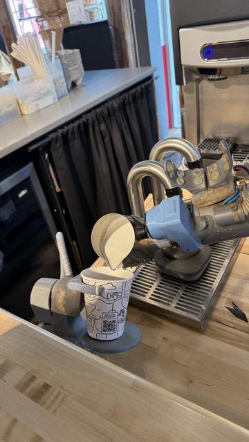 An Artly barista bot pouring milk