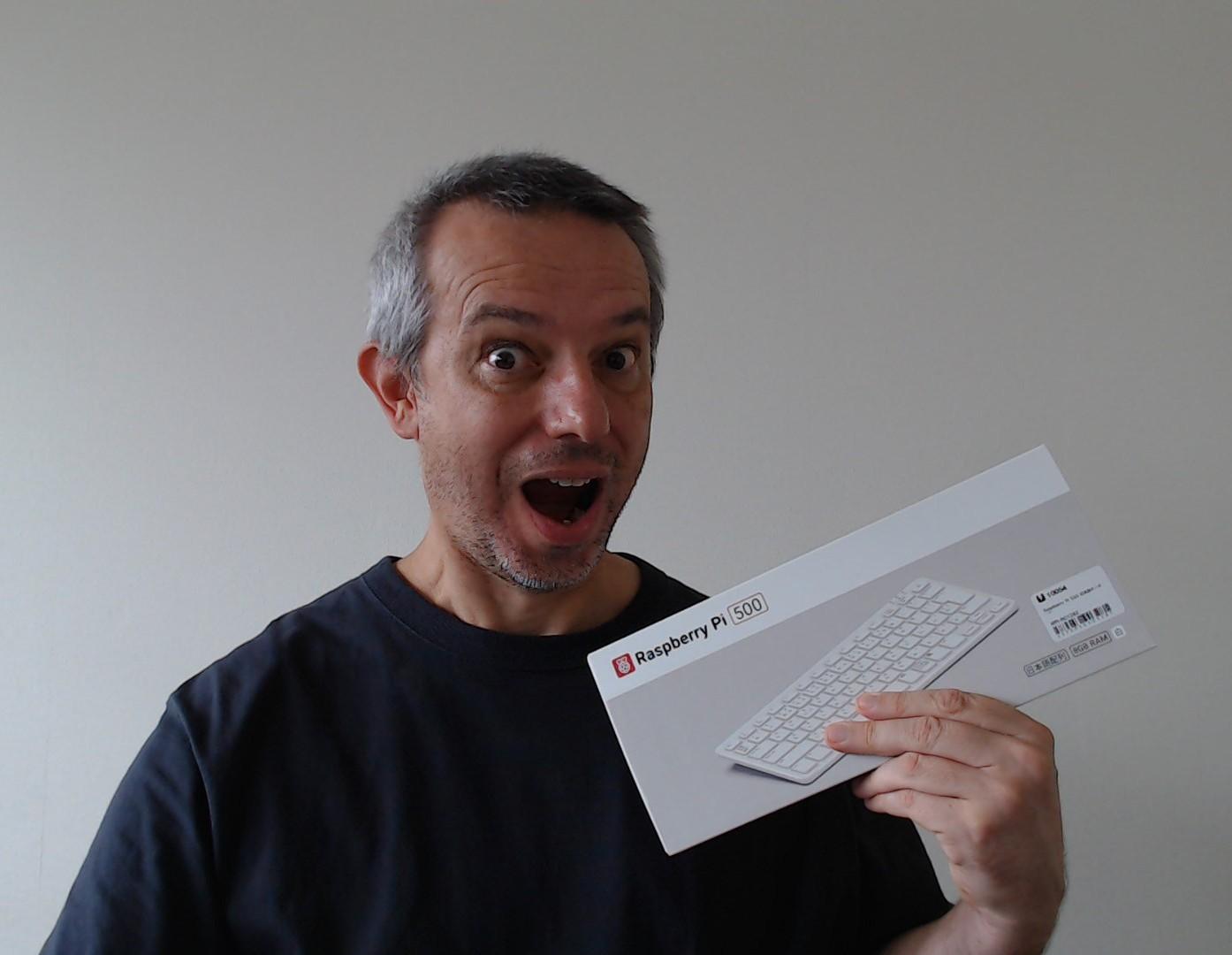 A selfie where I look excited because I'm holding a brand new Raspberry Pi500 in my hand (still in its box)