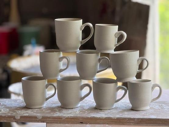 9 small demitasse coffee cups stacked on each other.  They are wheel thrown and hand pulled. Still need to be decorated