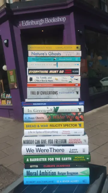a stack of paperback and hardback new non-fiction releases outside the Edinburgh Bookshop, on a bright, spring day
