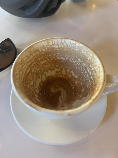 Photo of an empty cup of coffee on a white tabletop.