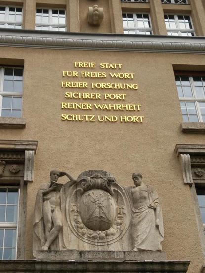 Vergoldeter Schriftzug an der Fassade des Altbaus: „Freie Statt / für freies Wort / freier Forschung / sichrer Port / reiner Wahrheit / Schutz und Hort“