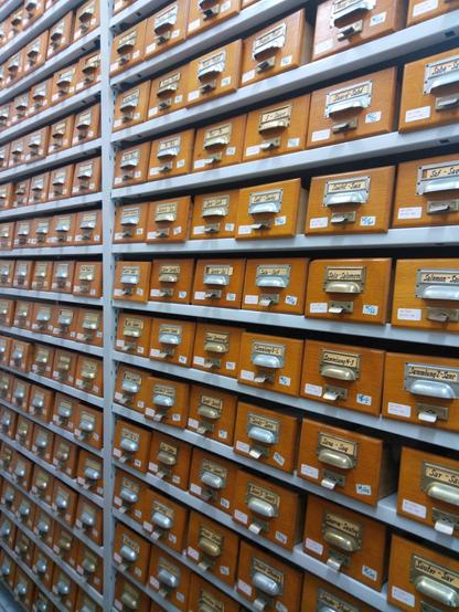 Blick auf die in hohen Metallregalen eingelagerten Karteikästen des früheren Bibliothekskatalogs