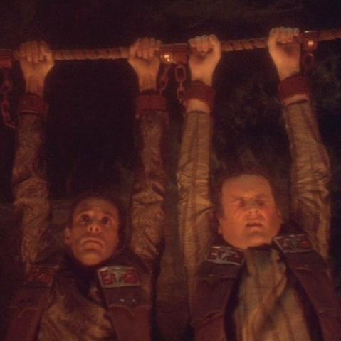 Scene from "Star Trek - Deep Space Nine": Bashir and O'Brien hanging from a rope, looking suffering.