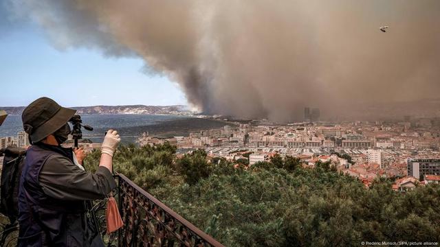 People take pictures of smoke at a lookout above Marseille 