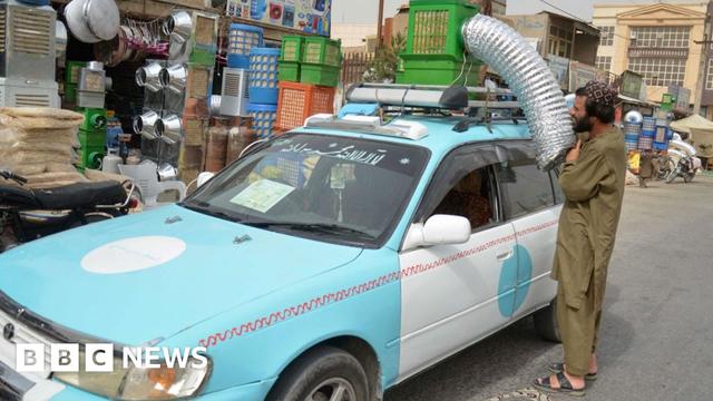 A taxi driver position an air conditioning unit on top of his vehicle.