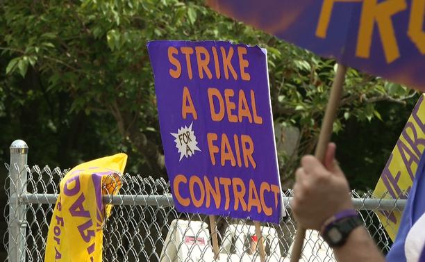A purple sign with orange letters says "strike a deal, fair contract."