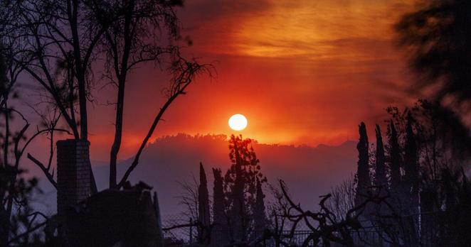 ALTADENA, CA - JANUARY 8, 2025: A smoky haze fills the dusk landscape as a home smolders in the foreground during the Eaton fire on January 8, 2025 in Altadena, California. (Gina Ferazzi / Los Angeles Times)