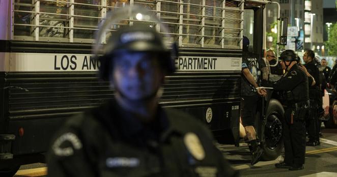 LOS ANGELES, CA - JUNE 12, 2025: Protesters with zip ties on their wrists are loaded onto a bus after being arrested for defying the 8PM curfew and for failing to disperse on Alameda Street during anti-immigration raid protests on June 12, 2025 in Los Angeles, California.(Gina Ferazzi / Los Angeles Times)
