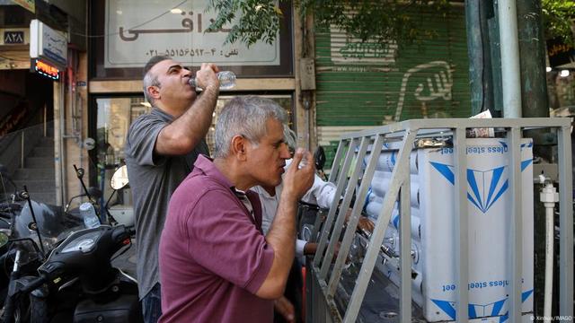 Zwei Männer trinken an einer Wasserstation