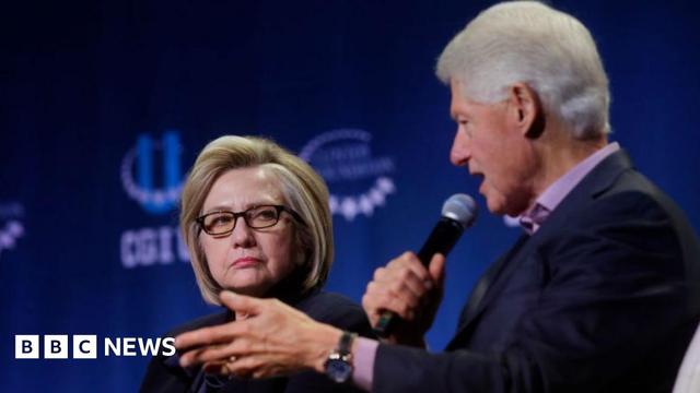 A file photo of Bill and Hillary Clinton on stage at an event - Bill is speaking into the microphone