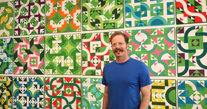 Artist Ben Millett poses for a portrait in front of "If I Had Said Yes," a multi-piece artwork made up of 21 individual quilts created specifically for the exhibition.