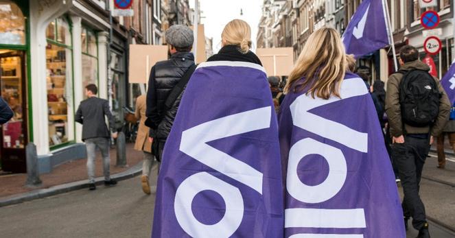 2 mensen lopen met een volt vlag op hun rug
