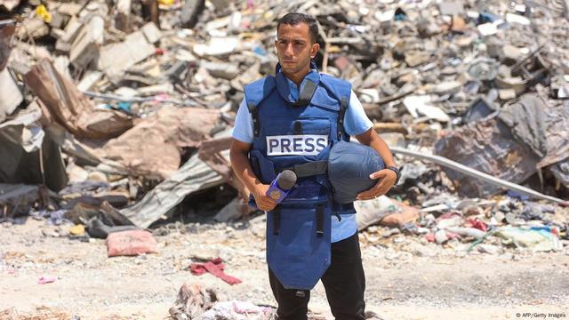 Anas Al-Sharif is seen standing in front of a pile of rubble inside Gaza