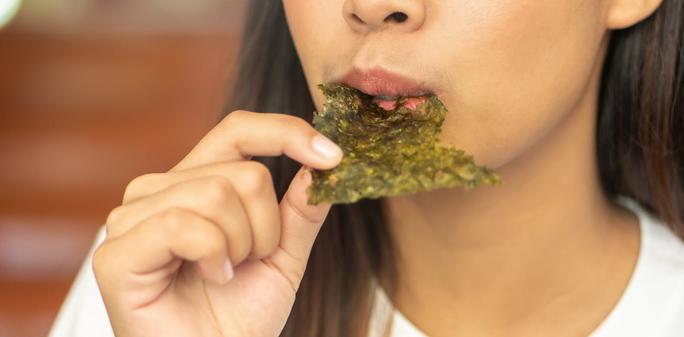 A woman eating a seaweed sheet. | 9nong/Shutterstock