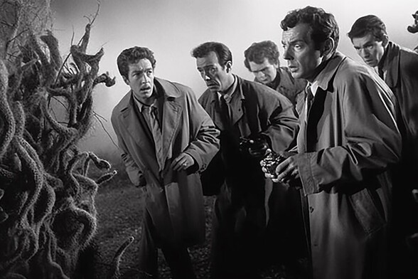 Five people in trenchcoats looking fearfully at a strange plant