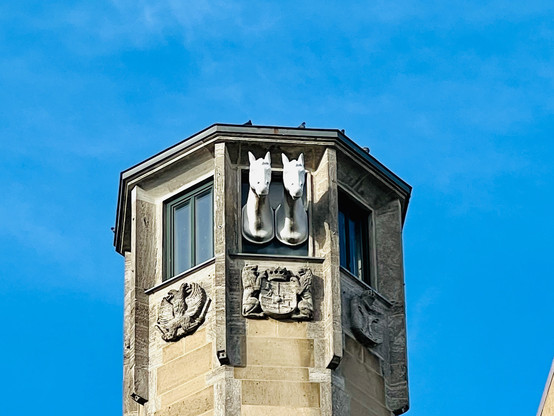 Photo if the Richmodis Tower on Neumarkt in Cologne with the two horse heads staring out from the top of the tower. Source: