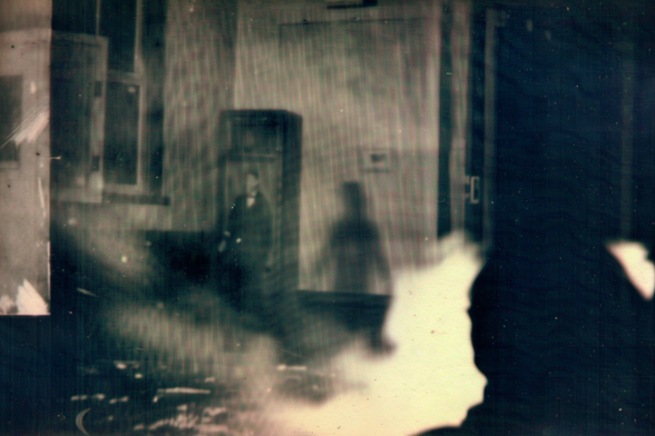 A view of a room filled with a fiery or luminous matter, behind which is a man and what doesn’t look like his shadow