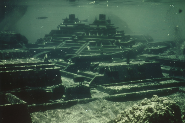 The ruins of an ancient city at the bottom of the ocean, with stepped pyramids and a giant fish or possibly a submarine passing by