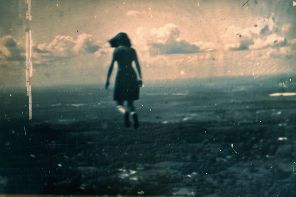 A woman hovers in vertical posture high above a wooded area