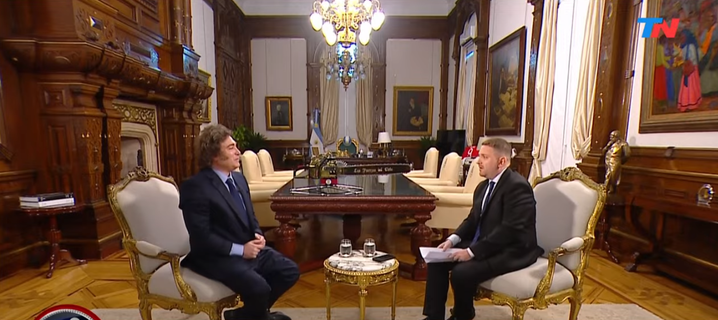Argentine president Javier Milei sits in front of his interviewer in a large room adorned with wood and gold in the government house. In the center a golden chainsaw is on display.