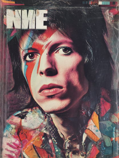 The image is a vibrant and textured magazine cover featuring a close-up portrait of a person with a distinct and colourful lightning bolt makeup across their face. The makeup has bold red, blue, and orange tones, creating a striking contrast against their pale skin. The person's expression is neutral, with full lips and cast slightly upward eyes. The background contains an abstract mix of colours and shapes, resembling a collage of various hues including reds, oranges, and blues. The magazine's title "NNE" is prominently displayed in large, bold white letters at the top left of the cover. The overall image gives a retro and artistic impression, with a worn and slightly creased texture suggesting age or wear.
