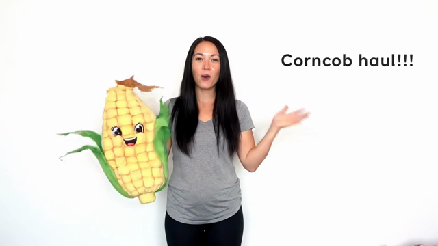 A young woman saying "Corncob haul" and smiling, She holds a large plush corncob that morphs around and becomes a onesie, which morphs onto her. 