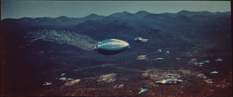 Metallic flying objects over a dark, hilly landscape at night.