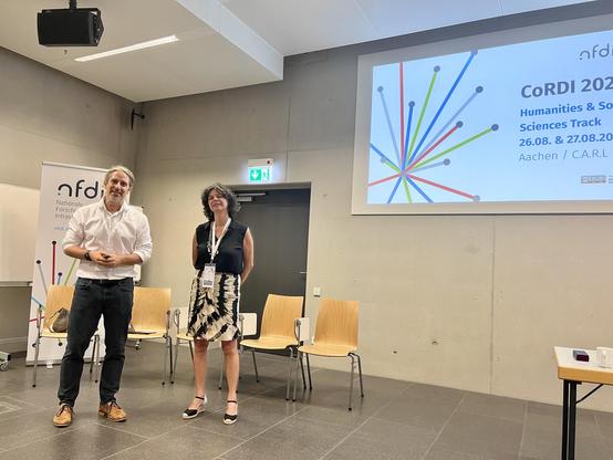 Torsten and Mercé standing in front of the Humanities session presentation screen at CORDI 2025