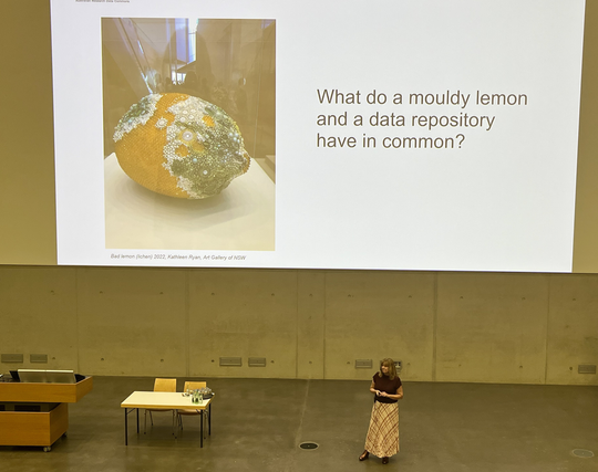 Rosie Hicks during her CORDI 2025 keynote in front of her presentation, showing a mouldy lemon as an artwork.