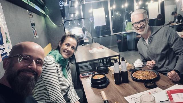 Together with Heiko and Anja sitting at a table. A pot of Korean food, a panncake and 2 bottles of beer on the table.
