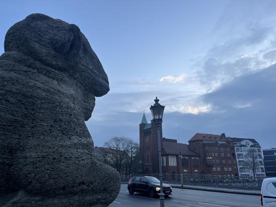 A chilly morning in Berlin in late November. Left ther is a ram made of stone towering one end of a Bridge over the river Spree.