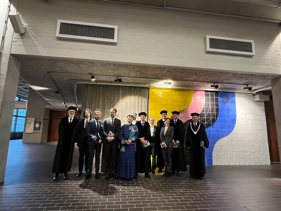PhD defense of Shuai Wang at VU Amsterdam. They really have a rather "traditional" procedure :wink: The picture was taken after the investiture of the newly promoted PhD in front of the bust of the founder of VU. FYI: the head of the committee is the professor with the chain around his neck. Only full professors are allowed to wear gown and hat. The candidate chose to wear traditional formal Mongolian clothing (traditional local clothing from your home country - besides wearing a black formal a…