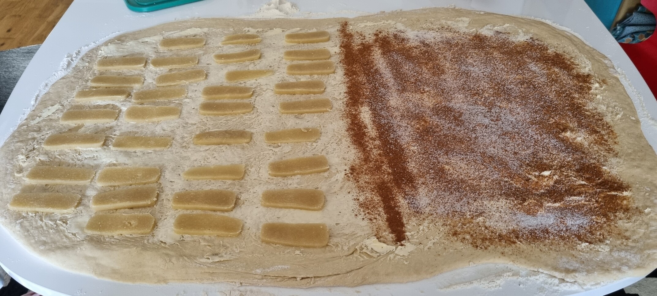 A dough spread out, ready to be rolled up. On the left there's one topping and on the right another. 