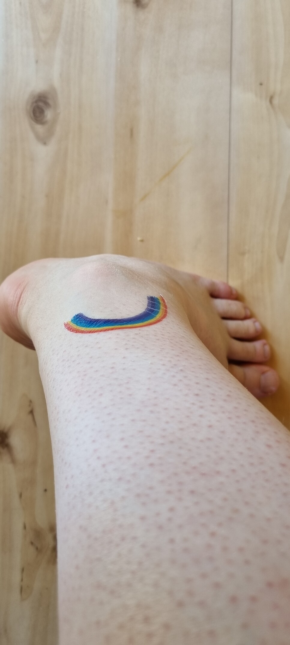 A picture of my leg with a foot at the end. There is a rainbow on it