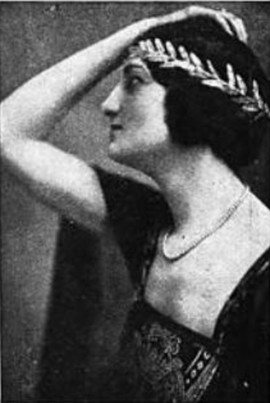 Frieda Klink, from a 1922 publication; a young white woman photographed in profile, one arm bent in front of her face, hand resting on top of her head; dark hair dressed with a laurel-style headband; wearing a dark dress with a deep, wide square neckline