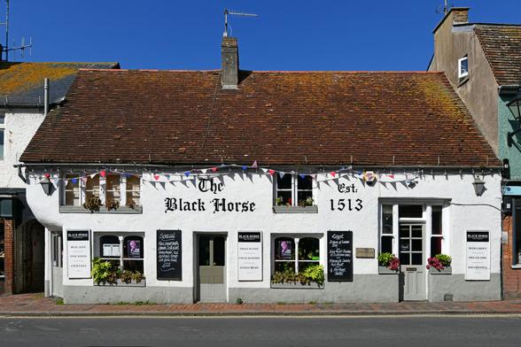 Photo of a rendered, timber-framed building thought to be C16, now a public house. Tiled, hipped roof running parallel to High Street. Jettied upper-storey to the south entrance. Grade 2 listed. Rottingdean