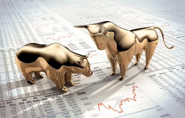 A golden bear squares off with a golden bull on a newspaper showing stock prices.