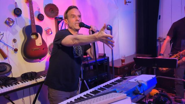 Person talking into microphone standing by keyboard