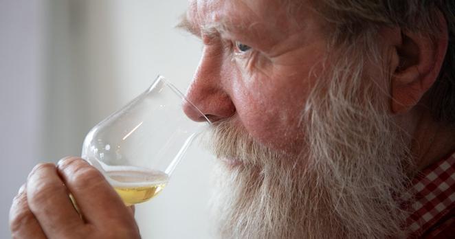 Erik Berkenkamp, ein Mann mit Bart, riecht an einem Glas Bier.