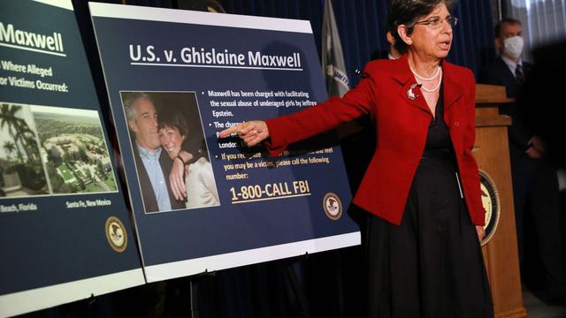 A woman in a red jacket points to a poster board titled "U.S. v. Ghislaine Maxwell" detailing charges and a contact number 1-800-CALL FBI, with images including Jeffrey Epstein.
