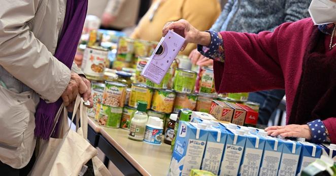 A volunteer at a food bank in Dortmund, Germany hands a food item to an older person on January 19, 2023. 