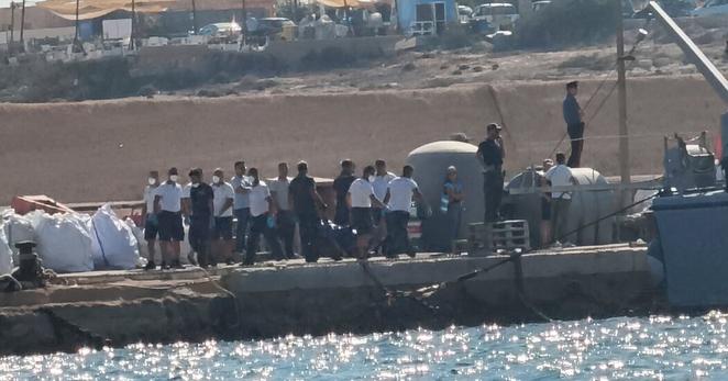 Italian Coast Guards officers carrying a body bag on the dock of the Lampedusa harbor on Wednesday.