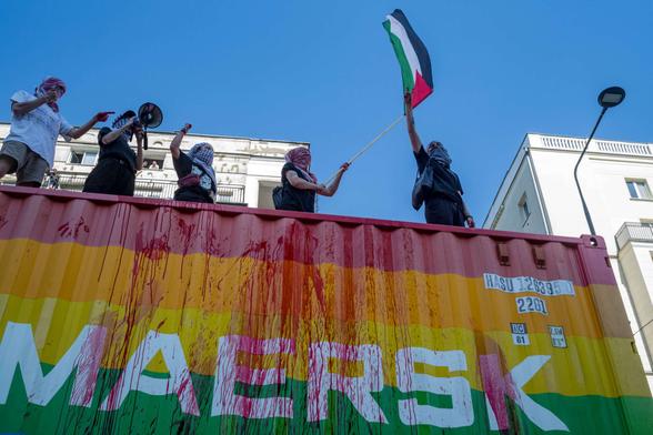 Protesters on top of a Maersk vehicle chant anti-genocide slogans while flying a Palestine flag on June 14, 2025, in Warsaw, Poland.