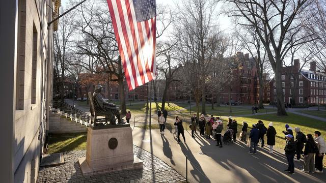 People take photos near a John Harvard statue, left, on the Harvard University campus, Jan. 2, 2024, in Cambridge, Mass. (AP Photo/Steven Senne, File)