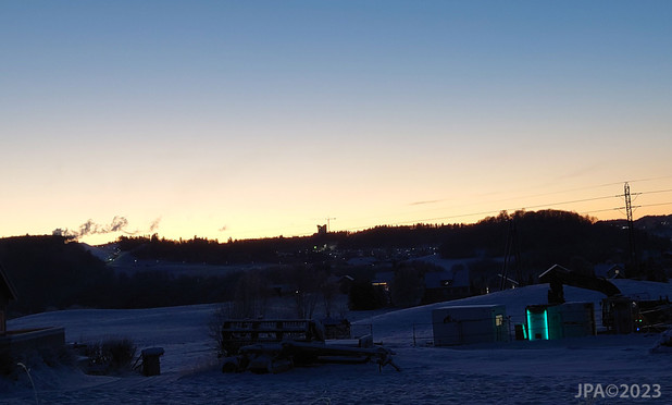 Kveldsbilde tatt fra Bratsbergveien viser Tillerområdet med det nye hotellet de bygger det nå, i siluett mot den orange solnedgangen.