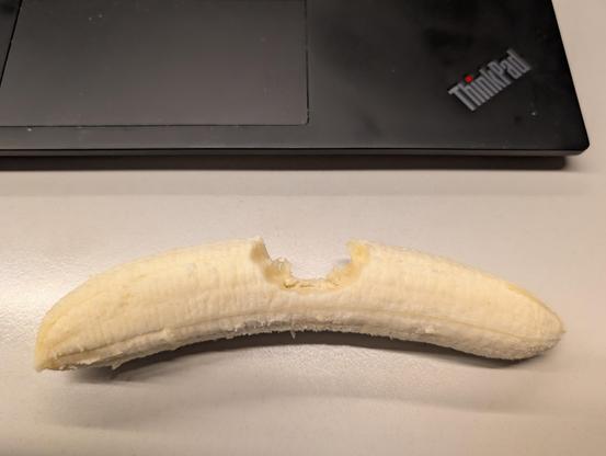 En naken banan på en hvit pult, ett bitt på midten.