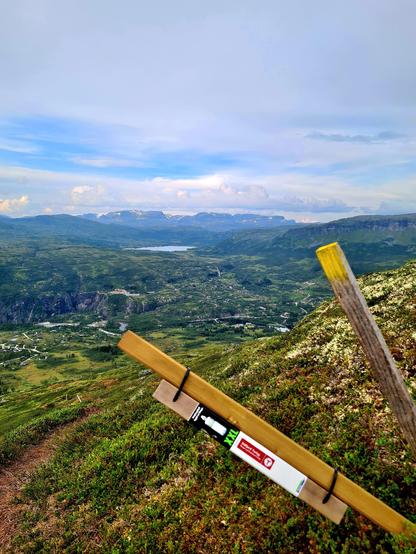 Bakgrunnen: Hardangerjøkulen, Isdalen med Isdalsvatnet, og nederst ser man Fossli med hyttefelt, hotell og parkeringsplasser. Forgrunnen: Svart stolpe fra Stolpejakten, høyt til fjells