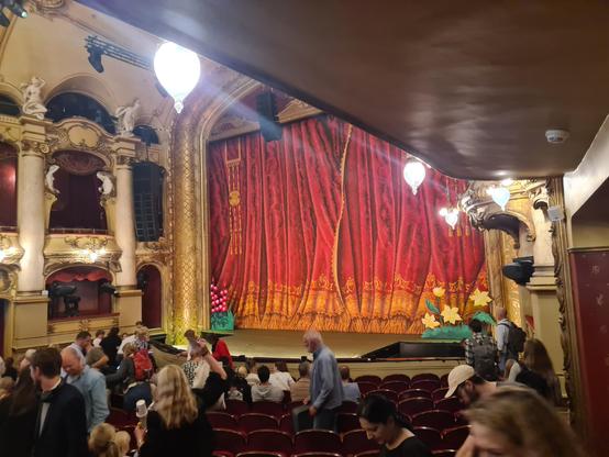 Hovedscenen på Nationaltheatret. Sceneteppet er nede. Store blomsterfigurer står foran teppet. Salen fylles med barnefamilier.