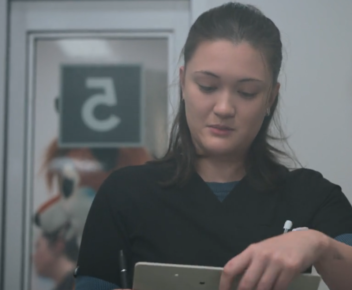 Screencap of The Pitt Season 2  Episode 9. you can only see Dr. Trinity Santos and in the background the Fursuit that is on a dryer outside the patient room (5)